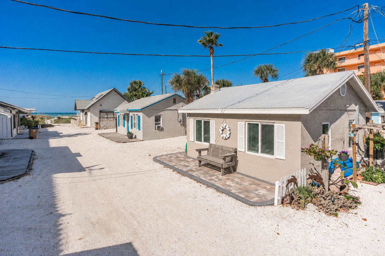 Una propiedad frente a la playa con varias casas de campo, una terraza de madera y un banco.