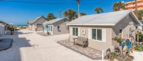 A beachfront property with multiple beach houses, a wooden deck, and a bench.