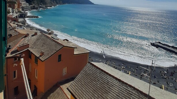 Une vue sur la côte, avec des bâtiments le long de la plage, un ciel dégagé et une montagne en arrière-plan.