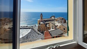Une vue depuis une fenêtre donnant sur une ville côtière, avec un imposant clocher et une plage.