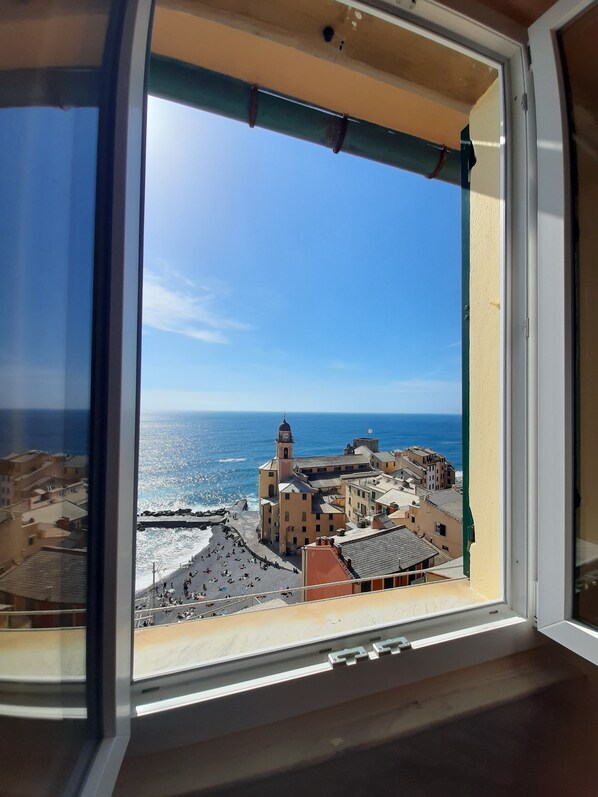 A view from a window overlooking a coastal town with a prominent clock tower and a beach. - Camogli vista mare (Camogli)