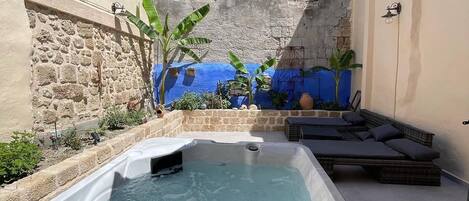 A hot tub with a stone wall and a blue-tiled wall in the background.