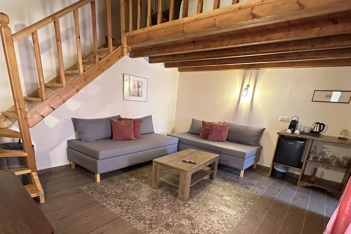 A cozy living room with a wooden staircase, a sofa set, a coffee table, and a television.