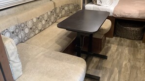 Interior compacto de autocaravana con sofá, una mesita y una cama.