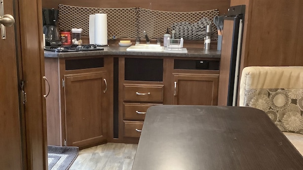 Una cocina compacta con armarios de madera, una encimera con cafetera y microondas.