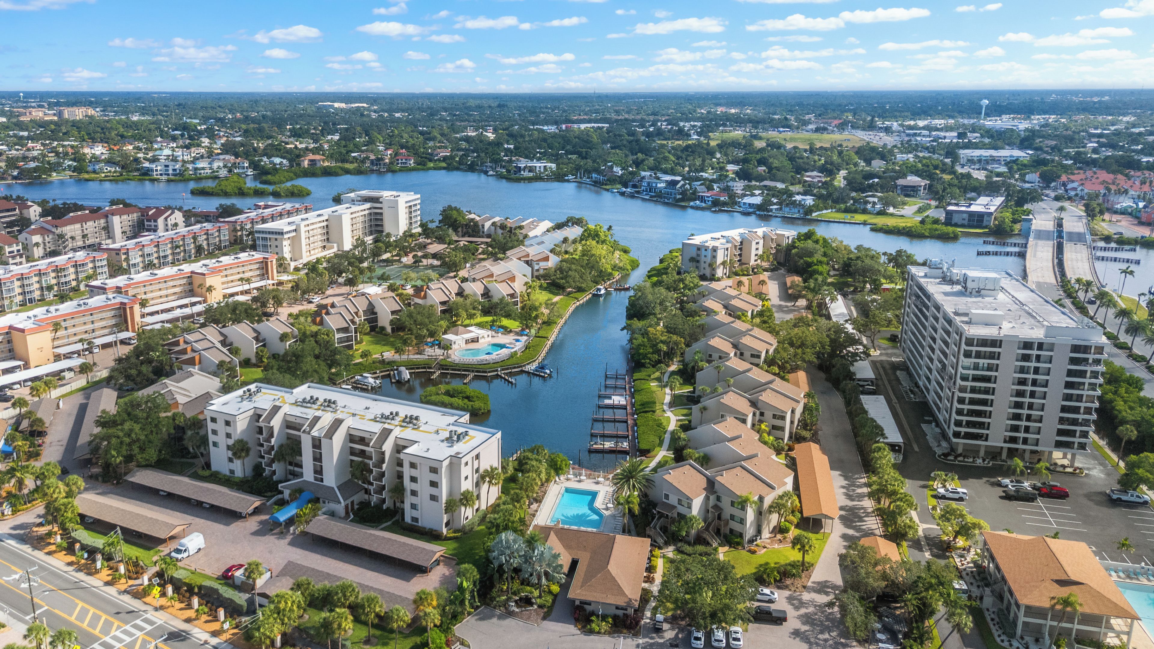 A high-rise hotel with multiple floors, a swimming pool, and a marina with boats.
