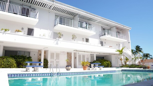 A multi-story hotel with a swimming pool, balconies, and potted plants. - Modern Paradise Island Condo near Atlantis resort & beach (Nassau)