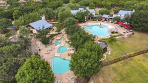 An aerial view of a resort with multiple swimming pools, lounge areas, and a fenced perimeter. - Lake View @ Hollows Resort: Pools, Pets, Balconies (Jonestown)