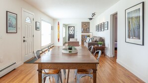 Un comedor con una mesa y sillas de madera, un sofá y una estantería.