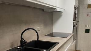 Een moderne keuken met een zwart spoelgedeelte, witte kasten en een betegelde spatwand.