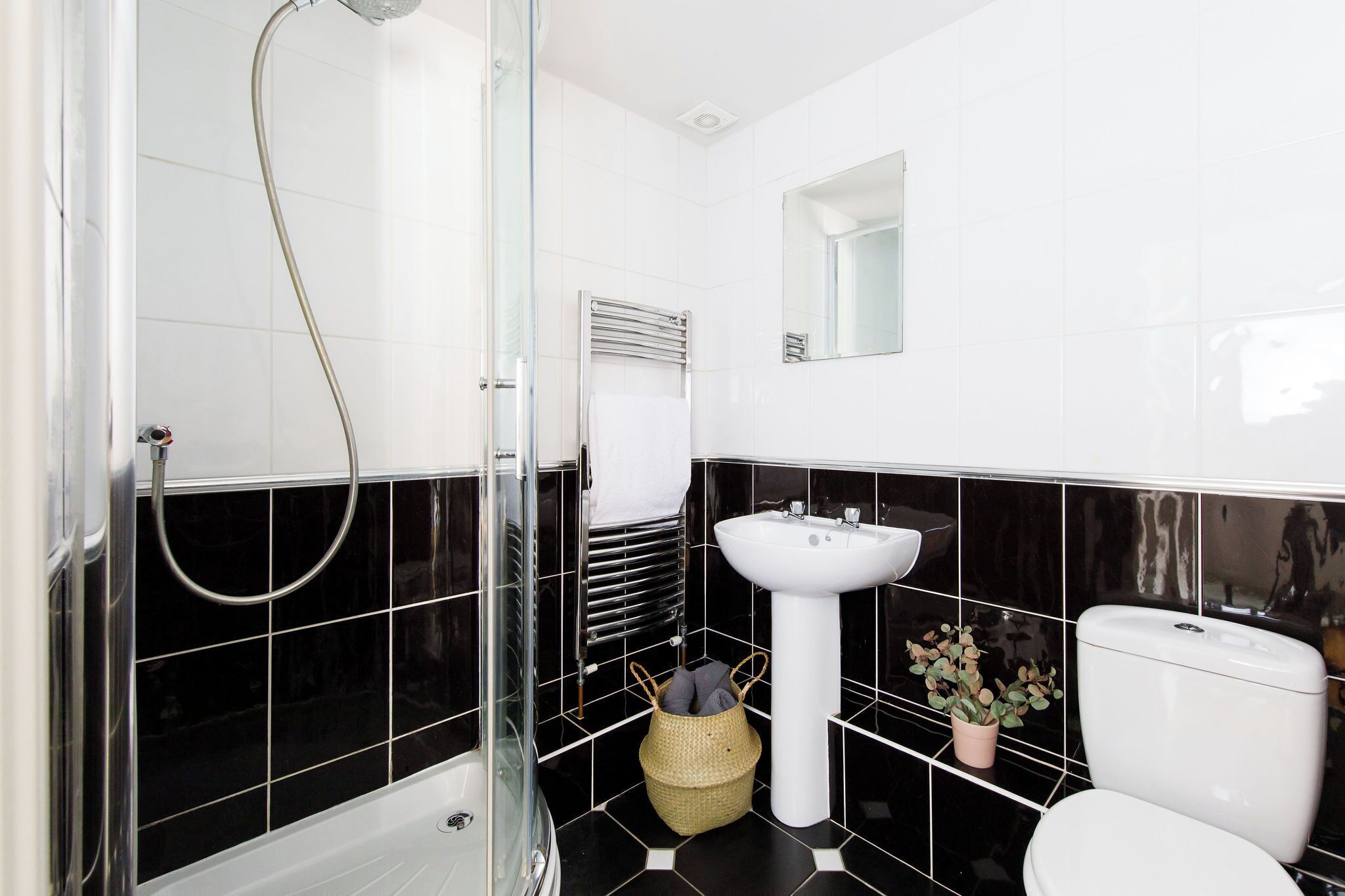 A bathroom with a glass shower enclosure, a white sink, and a toilet.