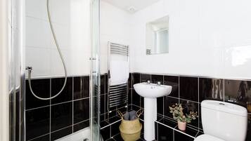 A bathroom with a glass shower enclosure, a white sink, and a toilet.