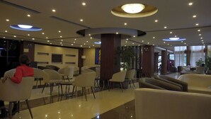 Eine Hotelhalle mit moderner Sitzmöbeln, einem Empfangsbereich und einer großen Chandelier.