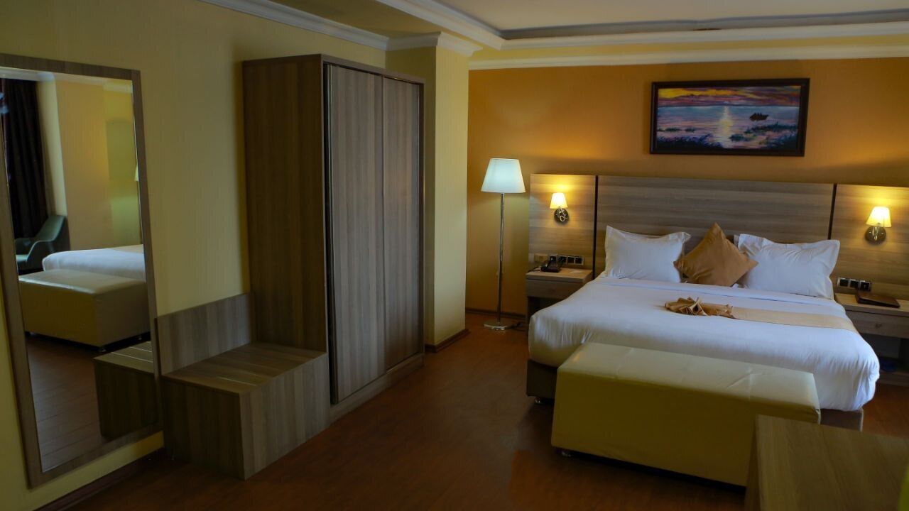 Hotelkamer met een groot bed, een garderobe, een nachtkastje, een lamp en een schilderij aan de muur.