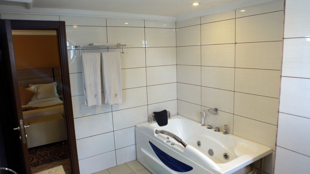 Un baño moderno con una bañera grande, azulejos blancos y un perchero visible.
