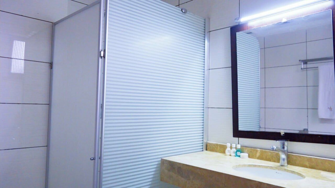 A bathroom with a large mirror, a sink with toiletries, and a shower enclosure.