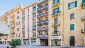 A multi-story building with balconies, a ground-level entrance, and a visible sign for a business. - Apartment Giallo by Interhome (Rapallo)