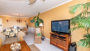 Una sala de estar con un sofá, una mesa de centro, un televisor y un altavoz.