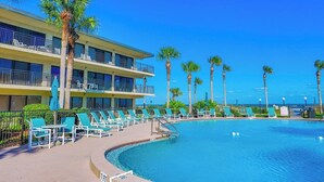 Un hotel con piscina, varios balcones y palmeras.