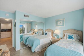 A room with two beds, a kitchenette, and a bathroom. - Parrot Party - Ocean House 319 (St. Augustine)