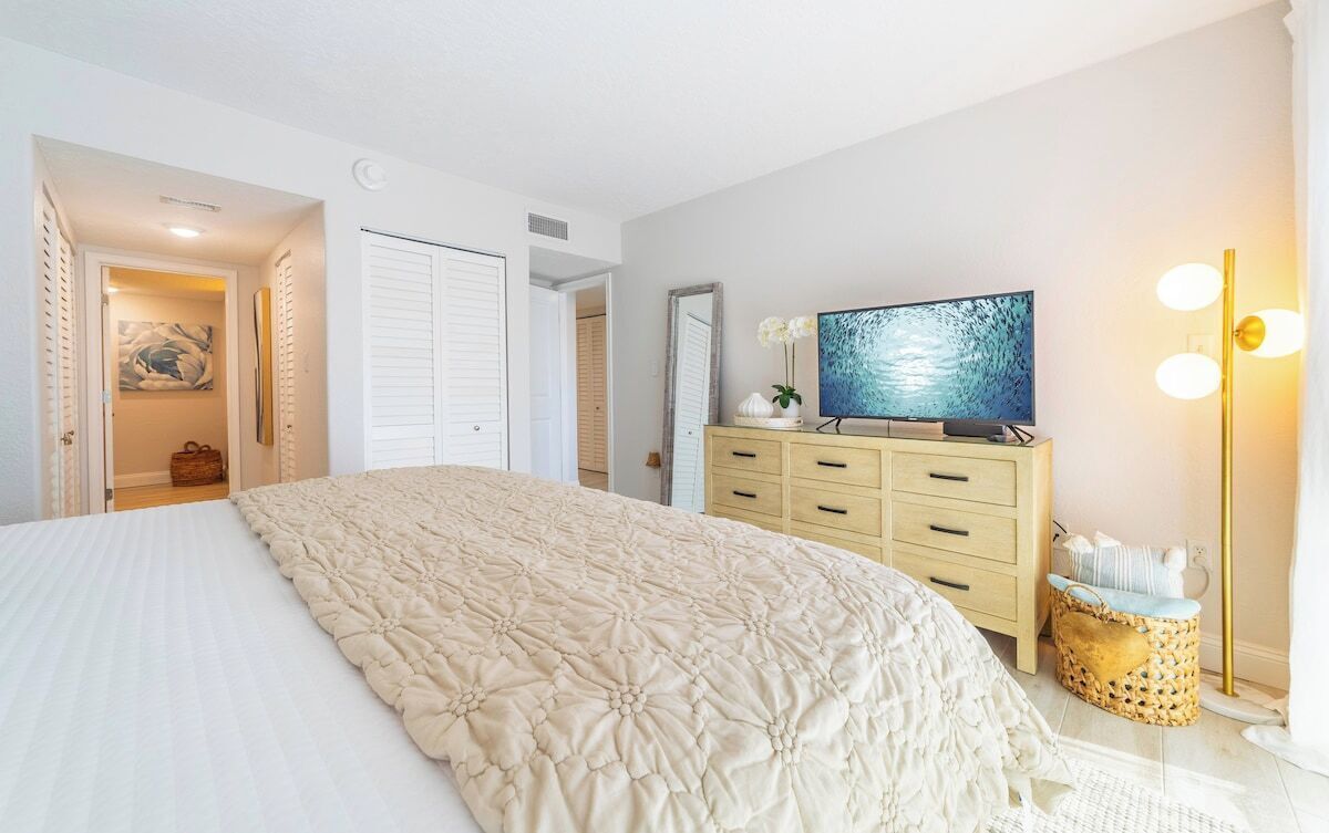 Ein Schlafzimmer mit einem großen Bett, einem Schminktisch, einem Fernseher und einer Lampe.