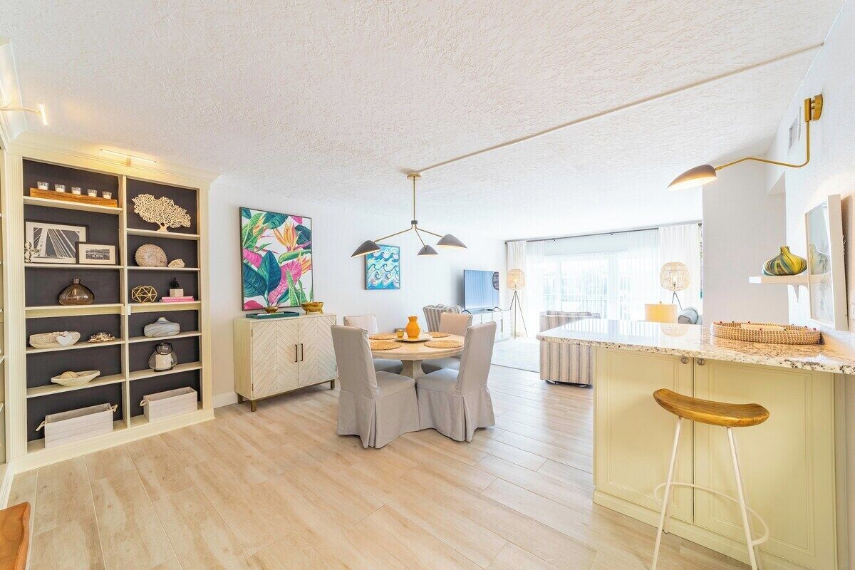 Una cocina moderna con zona de comedor, que incluye una isla central, taburetes de bar y varios objetos decorativos en estantes.