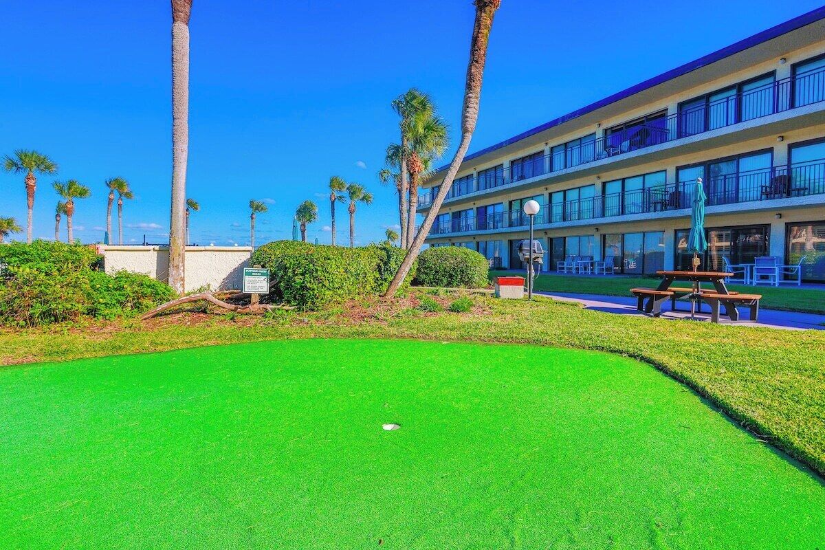 A golf course with a clear view of a hotel building in the background.