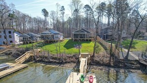 A lakeside property with a dock, a grassy lawn, and multiple houses.