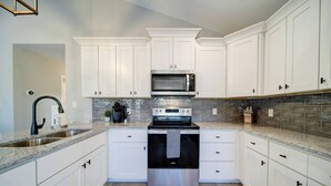 A modern kitchen with white cabinets, a stainless steel stove, and a microwave.