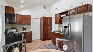 Une cuisine dotée de meubles en bois, d’un réfrigérateur en acier inoxydable, d’une cuisinière et d’un coin repas avec une table et des chaises.