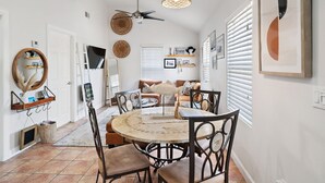Un espace repas comprenant une table ronde, des chaises, un ventilateur de plafond et un luminaire suspendu.