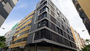 Ein mehrgeschossiges Gebäude mit moderner Architektur, das dunkle und helle Fassaden, große Fenster und eine auffällige Beschilderung für 'CONSTRUCCIONES Cristóbal Ortiz' zeigt.