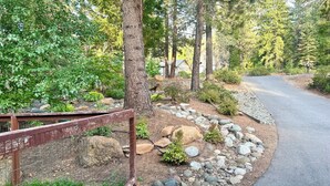 A landscaped area with a paved path, a wooden fence, and a variety of plants and rocks. - Stunning and Luxurious Riverfront home for 6 with two king beds. Pet Friendly! (Westwood)
