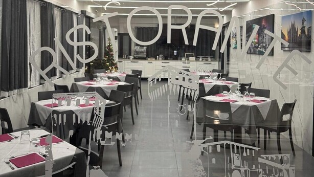 Un restaurante con mesas preparadas para comer, un árbol de Navidad y un cartel grande con la letra 'S' en la pared.