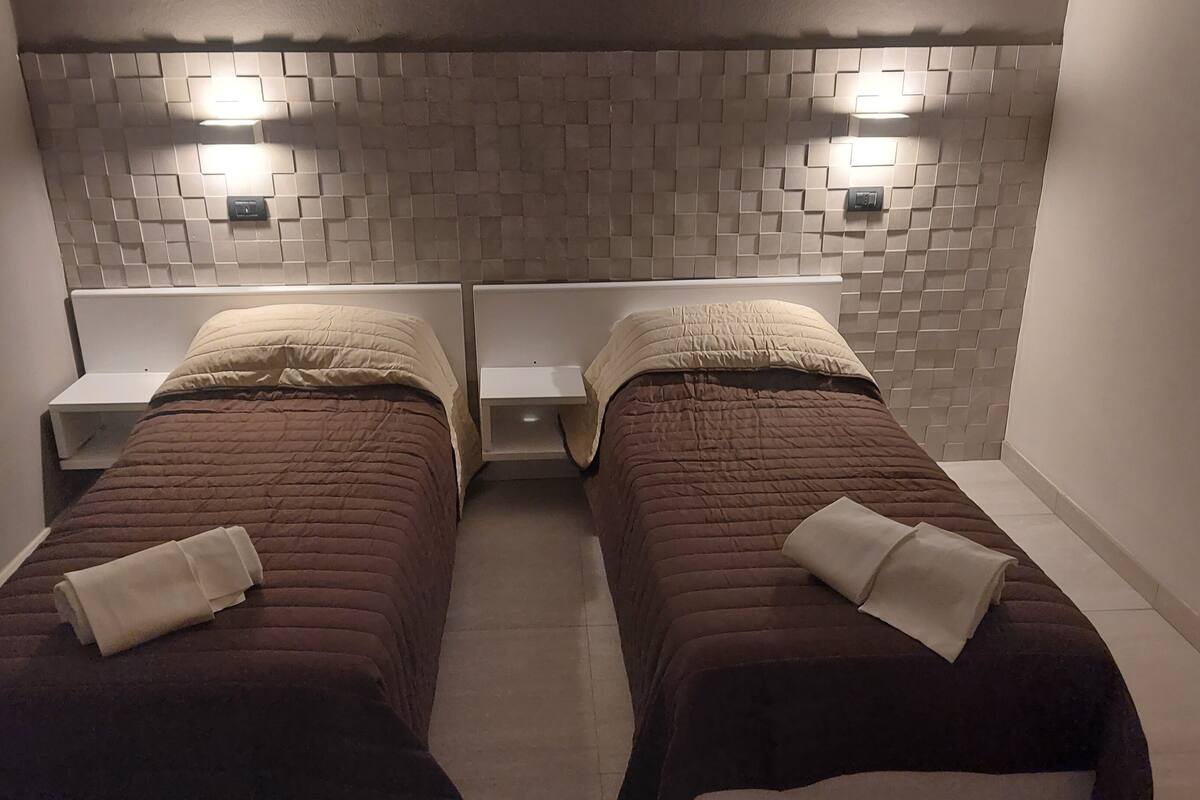 Une chambre avec deux lits, chacun doté d’une tête de lit et d’une table de chevet.