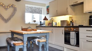 Een keuken met een houten tafel, een hond en een hartvormige decoratie aan de muur.