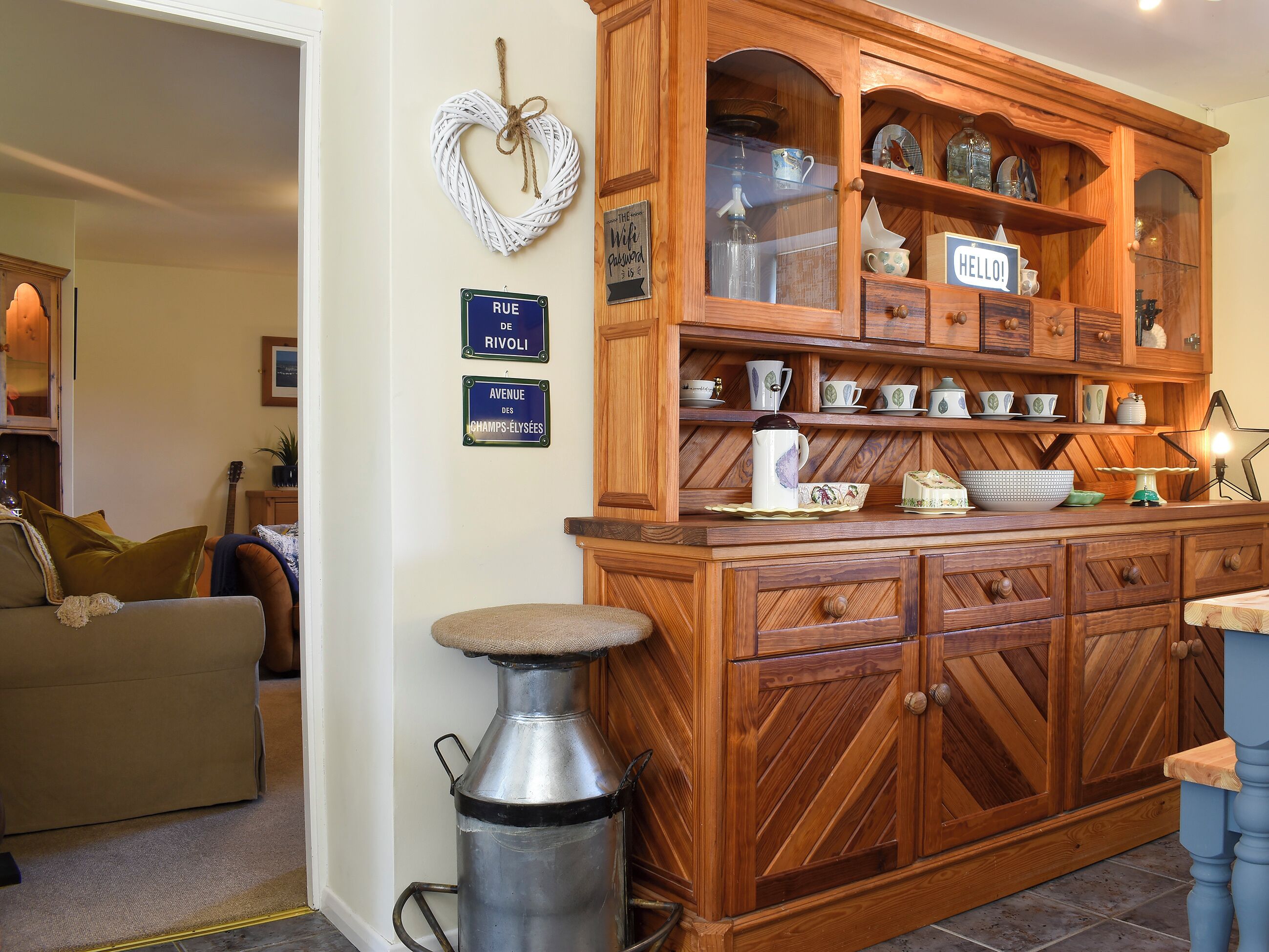 A kitchen with wooden cabinetry, a metal sink, and a heart-shaped decoration on the wall.