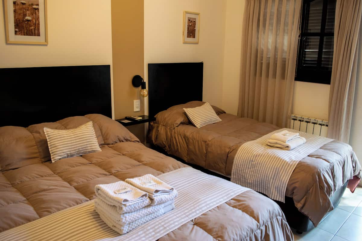 A hotel room with two beds, each with a headboard, a nightstand, and a lamp.