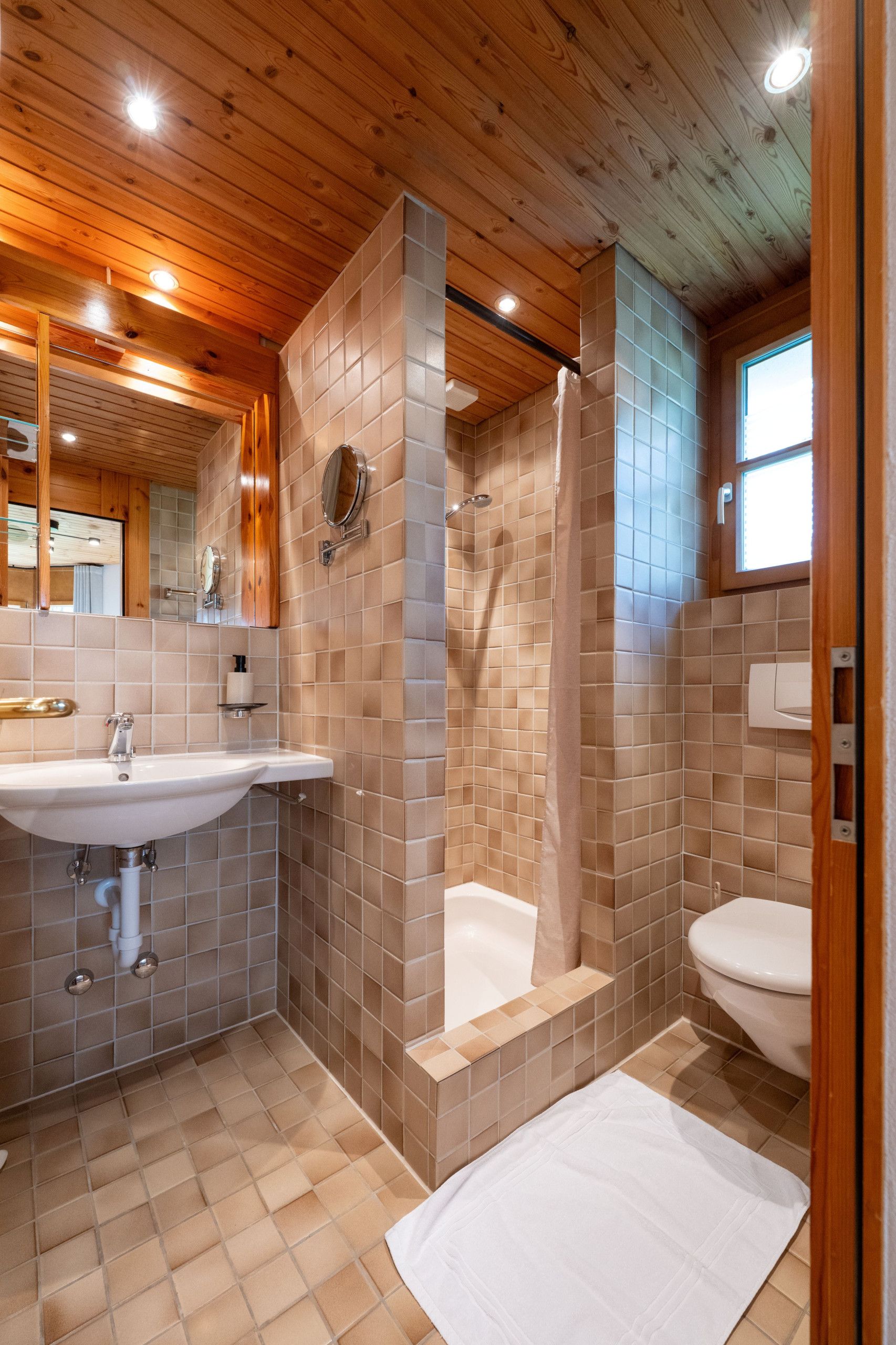 Un baño con techo de madera, un lavamanos, una bañera y un inodoro.