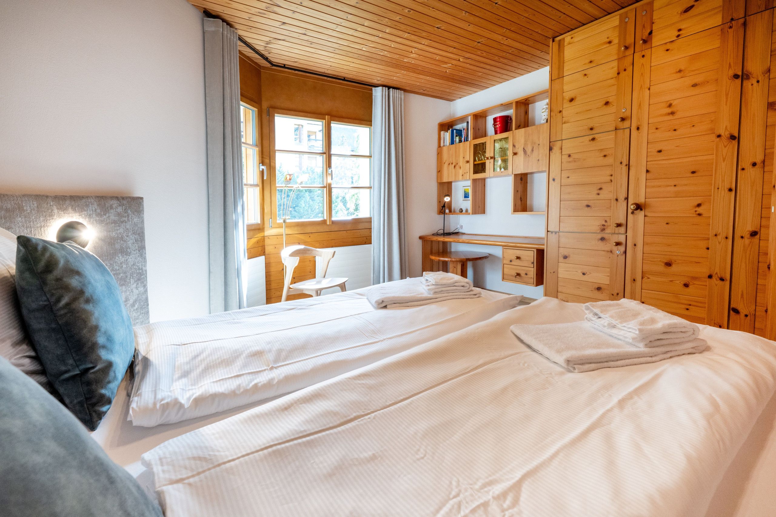 Una camera d'albergo con due letti, una scrivania e un armadio.