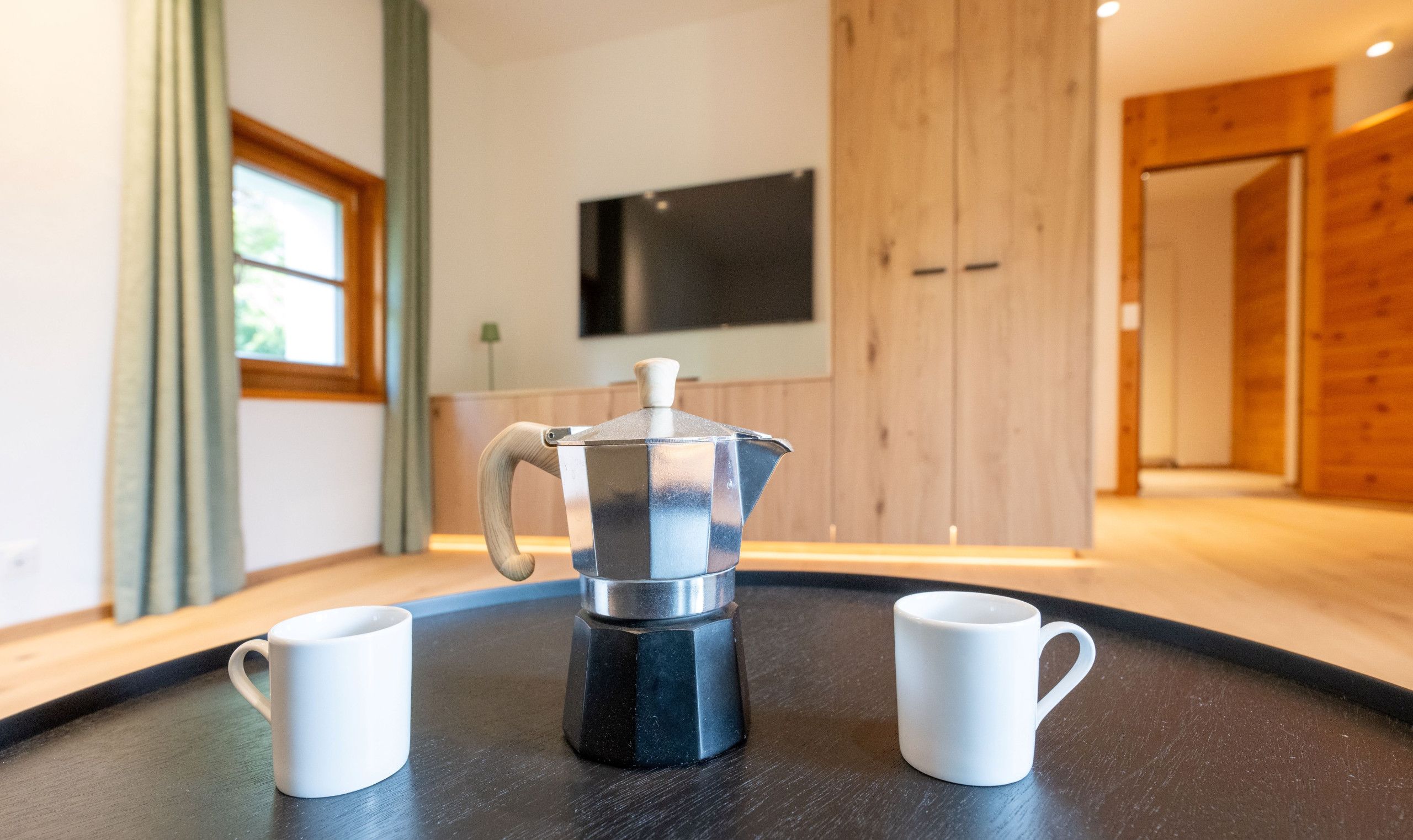 A modern kitchen with a coffee maker and two white mugs on a black countertop.