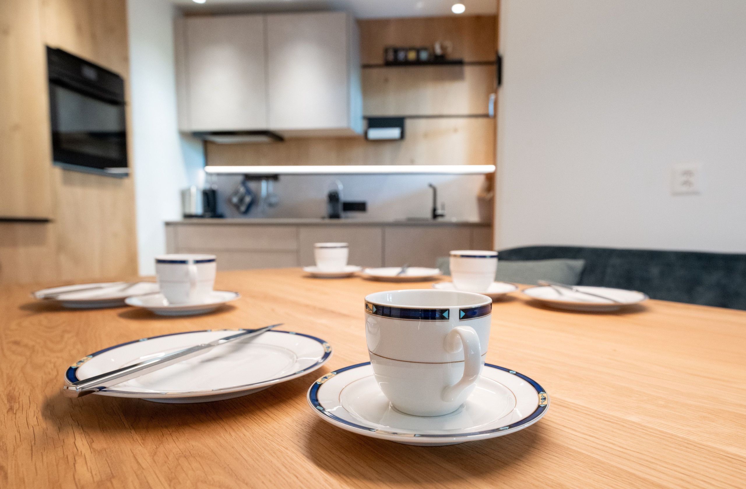 A dining table with plates, cups, and cutlery.
