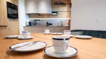 A dining table with plates, cups, and cutlery.