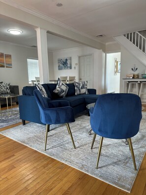 Una sala de estar con un sofá seccional azul, un sillón a juego y una alfombra estampada.