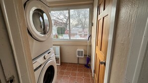 A laundry room with a washing machine, dryer, and a window overlooking a backyard. - POOL, 5 min walk to Jenks, 4 Bedroom, 4 car parking, beach badges, Fence, Pets (Point Pleasant Beach)