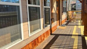 Eine überdachte Veranda mit Holzgeländern und einer Holzdielenfläche.