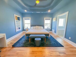 Relax in this serene bedroom with a large bed, a dresser, and a table, set against a wooden floor.