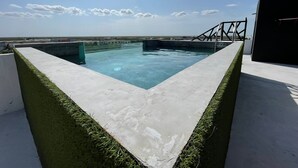 Una piscina en la azotea con vistas despejadas al cielo y edificios lejanos.