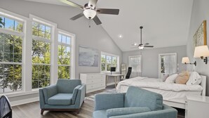 Quarto moderno com uma cama grande, duas cadeiras, uma escrivaninha e um ventilador de teto.