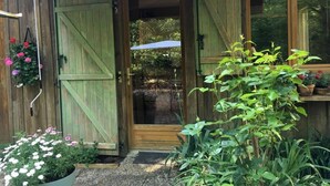 A rustic wooden building with a green door and a white awning. - B&B Les Truffières in the heart of nature (Trémolat)